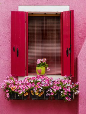 Açık pembe pencere yumuşak bir cazibe yayıyor, Burano 'nun canlı sokak manzarasına tatlı ve nazik bir aksan sunuyor.
