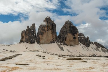 Dolomitlerin haziran ayındaki engebeli güzelliği: Karlı Tre Cime Pisti 'nin bazen sislerin arasından zirveleri ortaya çıkıyor.