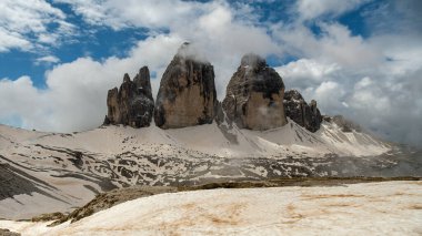 Dolomitler ortaya çıktı: Haziran sisinden yükselen tepelerle karla kaplı Tre Cime Pisti.