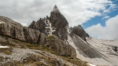 Haziran 'da Dolomitlerin eşsiz güzelliğini yakalayan yemyeşil çimenlerin ön planına karşı kar kaplı Kir Grupları' nın çarpıcı kontrastını deneyimleyin.