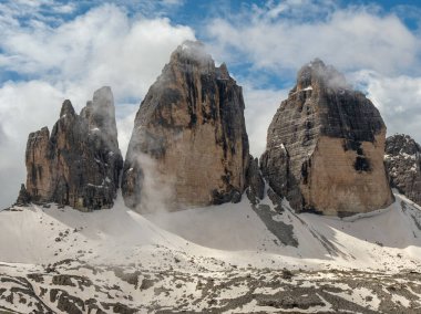 Haziran ayındaki Dolomitler: Tre Cime Pisti 'nde karla kaplı yollar ve bazen sisin içinden görünen tepeler.