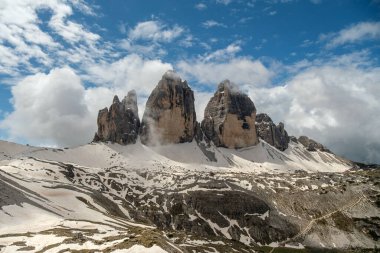 Tre Cime Pisti 'nde kar ve sisin içinde yürürken, Dolomite tepeleri puslu bulutların arasından yükseliyor.
