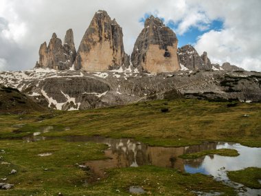 Haziran 'da Tre Cime Pisti' ndeki karlı yollarda Dolomite zirveleri ara sıra sisi gözetliyor..