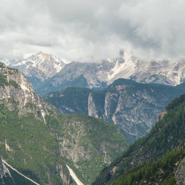 Haziran ayındaki Dolomitler: Öngörülemeyen sis ve bulutların arasından yükselen tepelerle karla kaplı Tre Cime Pisti