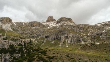 Haziran ayındaki Dolomitler: Destansı bir manzara için sisin içinden zirveler çıkan karla kaplı Tre Cime Pisti