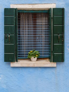 Yumuşak, açık mavi pencere, Burano 'nun sakin atmosferiyle uyum içinde, sakin bir cazibe yayar..