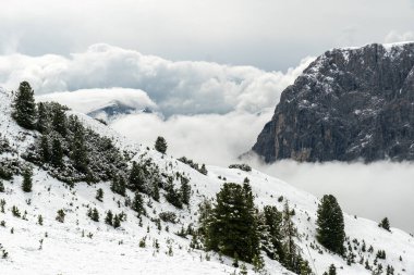 Haziranda görkemli Dolomitler, karla bezenmiş dağlarla ve beyaz bulutlarla kaplanmış