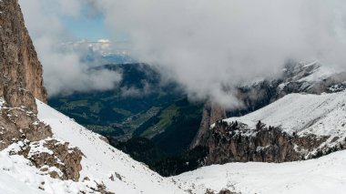 From the Cir Group trail, catch a glimpse of Selva di Val Gardena shrouded in mist and clouds. clipart