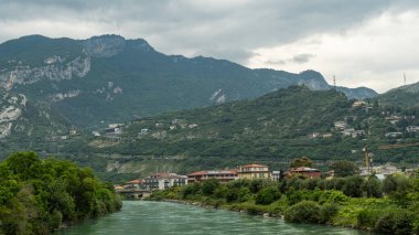 Witness the peaceful flow of Sarca River as it makes its way from Lago di Garda to Riva del Garda, blending seamlessly into the stunning lakeside landscape clipart