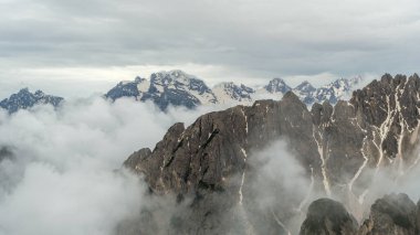 Haziran 'da Tre Cime Circuit Trail: Kar ve bulutlar Dolomite zirveleriyle karışıp hayranlık uyandırıcı bir sahne yaratıyor.