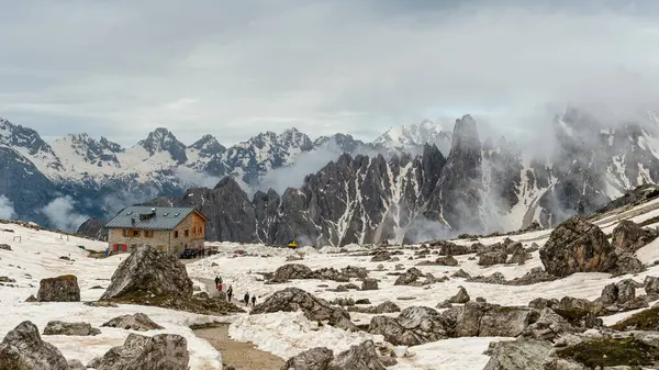 stock image Hiking Tre Cime Circuit in June: Snow and fog blending with the dramatic Dolomite summits.