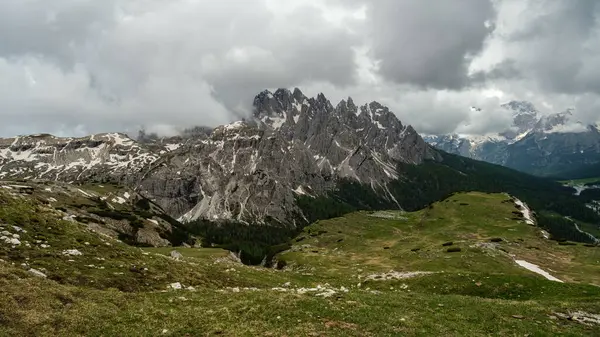 stock image Hiking Tre Cime Circuit in June: Snow and fog weaving around Dolomite summits for a magical view.