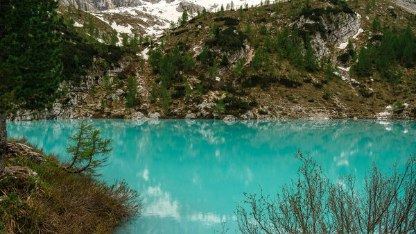 Experience the striking contrast of the Cir Groups snow-capped peaks against a foreground of lush green grass, capturing the unique beauty of the Dolomites in June