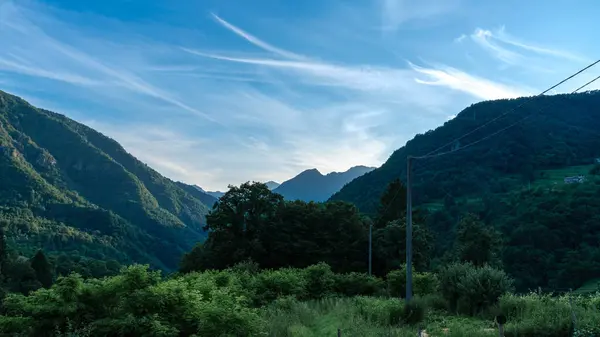 stock image As twilight settles over the Italian countryside, the lush, green peaks of the forested mountains create a serene and captivating evening panorama