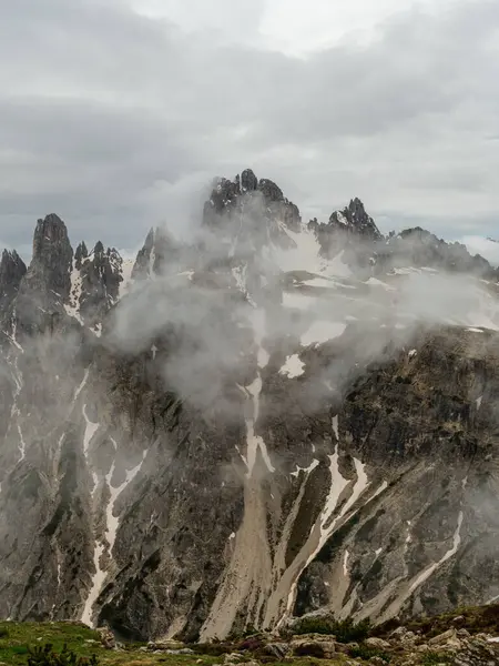 stock image Hiking through June snow on Tre Cime Circuit, with the Dolomites' peaks partially veiled in fog.