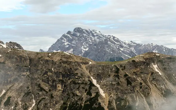 Tre Cime Pisti 'nde kar ve sislerin arasında yürürken Dolomite zirveleri ara sıra sisin içinden geçiyor.