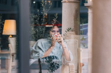 Güzel ve zarif bir kadının portresi hafif makyajlı, kahve yudumluyor, düşünceli ve nostaljik..