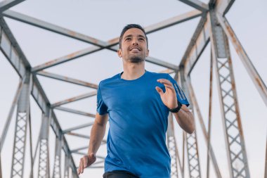 Gün batımında eski bir metal köprüde koşan genç bir sporcunun yakın çekimi, spor konsepti..