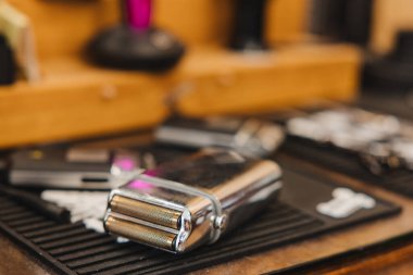 Parlak gümüş bir tıraş bıçağı ahşap bir masanın üzerine, bir makasın yanına yerleştirilir. Makas da masanın üzerinde. Masanın etrafına saçılmış birkaç şey daha var. Mesela bir şişe ve bir fincan.