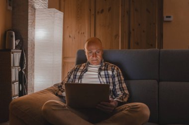 Adam mutlu teknoloji kullanıcısı, kanepede dizüstü bilgisayarla dinleniyor. Modern dizüstü bilgisayar sörfü, haber okuma, uzaklık online çalışma kavramı kullanan bir adam..