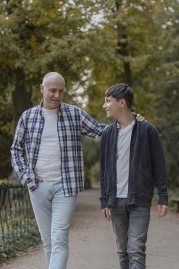 Baba ve oğul hayatları hakkında konuşarak ve dinleyerek doğal bir parkta yürürler. Sohbet.