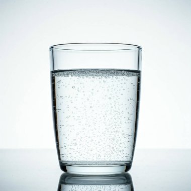 Beyaz zemin üzerinde buz küpleri olan bir bardak su.