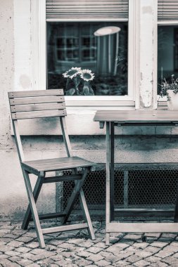 Sandalyesi, çiçekleri ve ön cephesi olan yarım masanın dikey görüntüsü