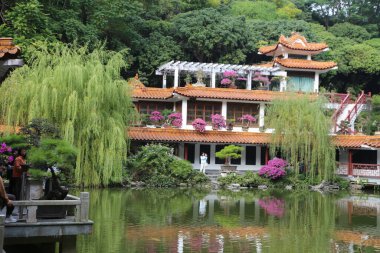 Önünde gölet olan güzel bir ev. Gölet ağaçlar ve çalılarla çevrili.