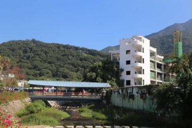 Arka planda bina olan bir nehir üzerinde köprü. Bina beyaz ve yeşil çatısı var.