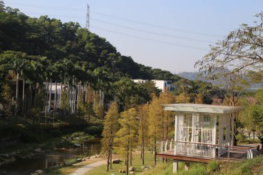 Beyaz pavyonu ve içinden akan bir nehri olan bir park. Köşk ağaçlarla çevrili ve nehir sakin.