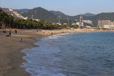 Bir sürü insan ve güzel bir okyanus manzaralı bir sahil. Manzara sakin ve huzurlu.