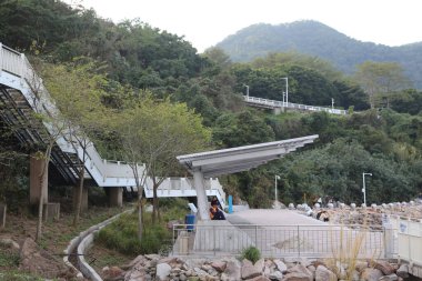 Bir grup insan büyük bir dağın önünde bir bankta oturuyorlar. Sahne huzurlu ve sakin, dağ güzel bir zemin sağlıyor. İnsanlar manzaranın tadını çıkarıyor gibi.