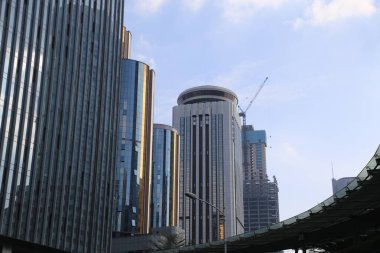 Ortasında yüksek bir bina olan bir şehir silueti. Gökyüzü açık ve güneş parlıyor.