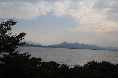 Arka planda dağlar olan güzel bir göl manzarası. Gökyüzü bulutlu ve su sakin.