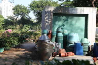 Binanın dışında saksı ve saksı yığını var. Tencereler çeşitli boyut ve renklerde ve dağınık bir şekilde yığılmış. Sahne dağınıklık hissi veriyor.
