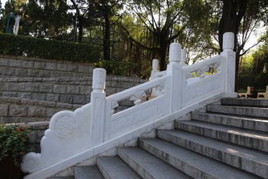 Beyaz korkuluklu ve beyaz tırabzanlı taş bir merdiven. Tırabzanın üzerinde bir tasarım var.