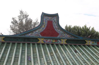 Kırmızı aksanlı yeşil bir çatı ve arka planda beyaz bir gökyüzü. Çatı çok fazla detayla süslenmiş ve görüntünün genel havası huzurlu ve huzurlu.