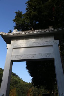 Arka planda mavi gökyüzü olan beyaz bir kemer yolu. Kemer yolu bir sürü ayrıntıyla süslenmiş.