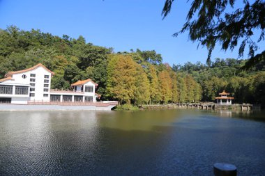 Arka planda evi olan bir göl. Ev beyaz ve kırmızı bir çatısı var. Göl sakin ve huzurlu.