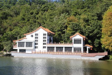 Kırmızı çatılı büyük beyaz bir bina göldeki bir teknede oturur. Binanın bir sürü penceresi var ve o bir restoran. Göl sakin ve huzurlu.