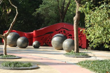 Kırmızı duvarı ve siyah topları olan bir park. Toplar bir daire şeklinde dizilir ve duvarın önüne yerleştirilir. Sahnenin sakin ve huzurlu bir havası var.