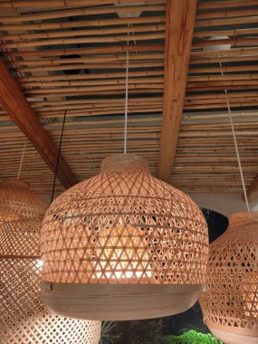 Tavandan sarkan bir demet ahşap lamba. Lambaların hepsi farklı boyutlarda ve şekillerde, ama hepsinin dizaynı. Lambalar yanıyor, sıcak ve rahat bir atmosfer yaratıyor.