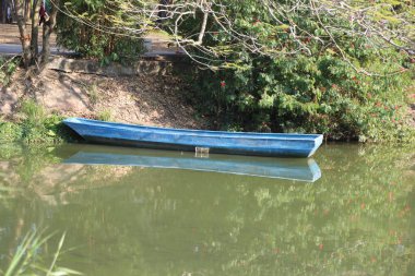 Gölde mavi bir tekne oturuyor. Su yeşil ve görünen tek şey tekne.