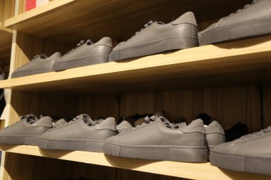 Rafta bir sıra ayakkabı, hepsi gri renkli. Ayakkabılar düzgünce dizilmiş ve birkaç çift ayakkabısı var.