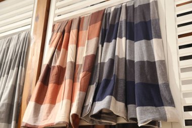 Bir sıra ekose battaniye askıda asılı. Renkler kahverengi, mavi ve beyaz.