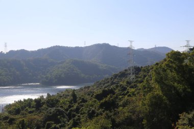 Önünde göl olan güzel bir dağ sırası. Gökyüzü açık ve güneş parlıyor.