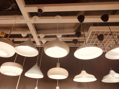 Tavandan sarkan bir sıra beyaz lamba. Aydınlatma armatürlerinin hepsi farklı şekil ve boyutlarda.