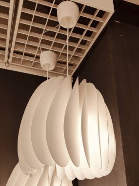 Tavandan sarkan beyaz bir lamba. Lamba yanıyor ve ışık tavanda parlıyor.