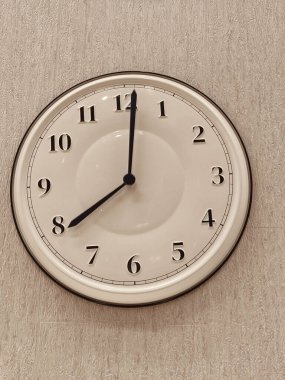 Siyah elli, saati 10: 10 olarak gösteren beyaz bir saat. Saat yuvarlak ve siyah bir yüzü var.