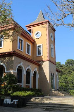 Yüksek kulesi ve tepesinde penceresi olan büyük bir bina. Bina sarı ve kahverengi.